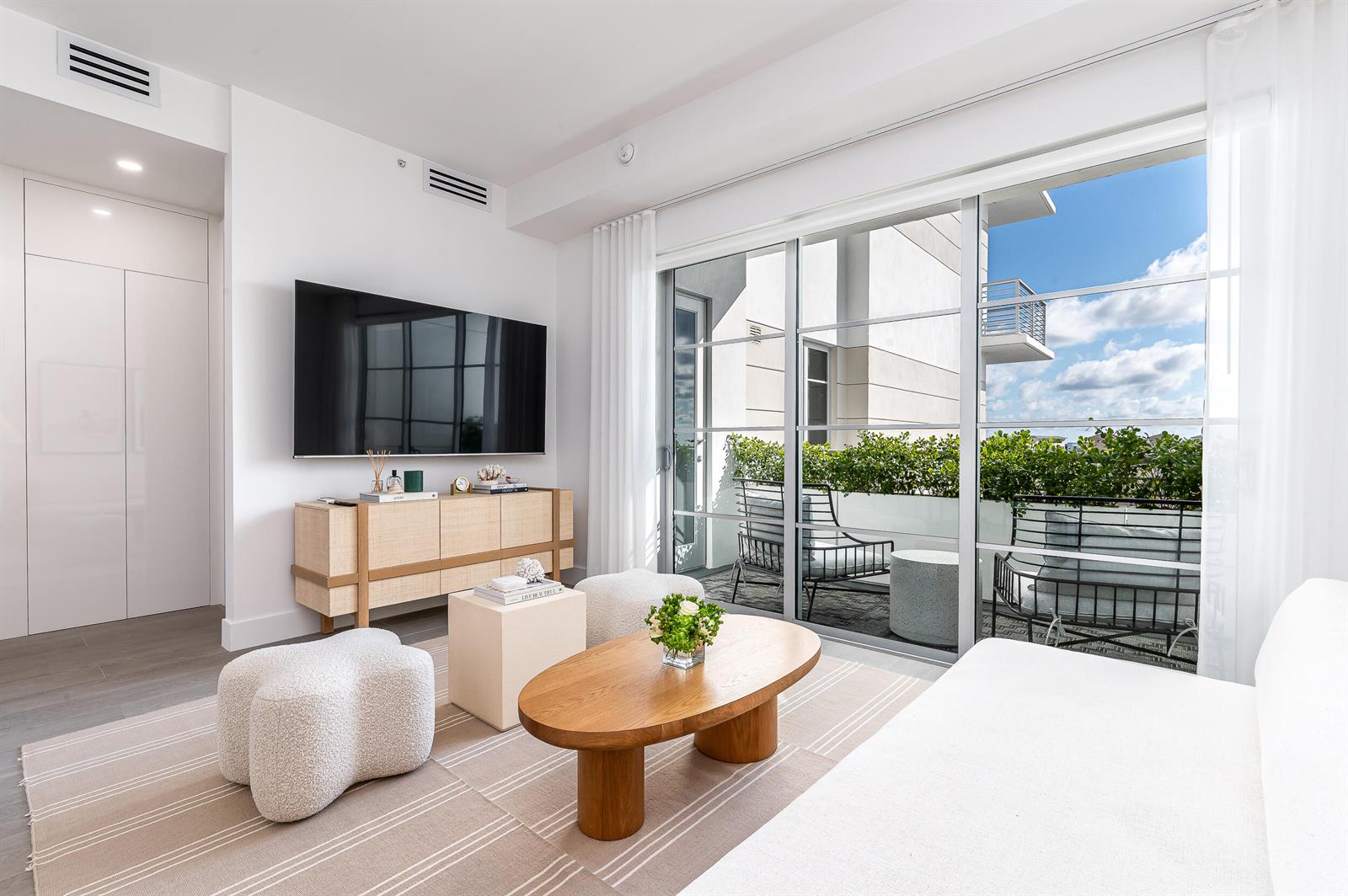 A modern living room features a television, wooden console, coffee table, and a balcony view — 155 E Boca Raton Road # 1008, Boca Raton FL 33432, BOCA RATON, FL