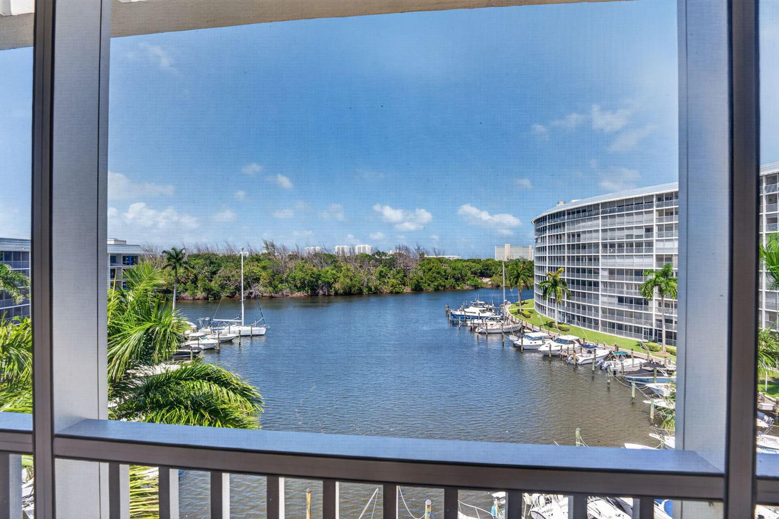 A view from a screened balcony overlooking a canal with docked boats and apartment buildings — 1427 E Hillsboro Boulevard # 628, Deerfield Beach FL 33441, DEERFIELD BEACH, FL