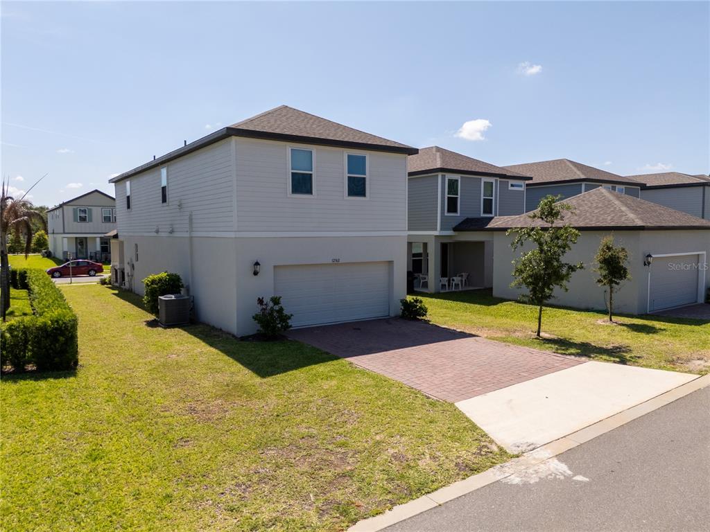 A two-story house with a two-car garage, light-colored siding, and a brick-paved driveway — 12362 BRACCO STREET, WINTER GARDEN, FL
