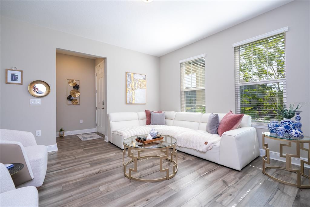 A living room features a white sectional sofa, a glass coffee table, and wood-look flooring — 12362 BRACCO STREET, WINTER GARDEN, FL