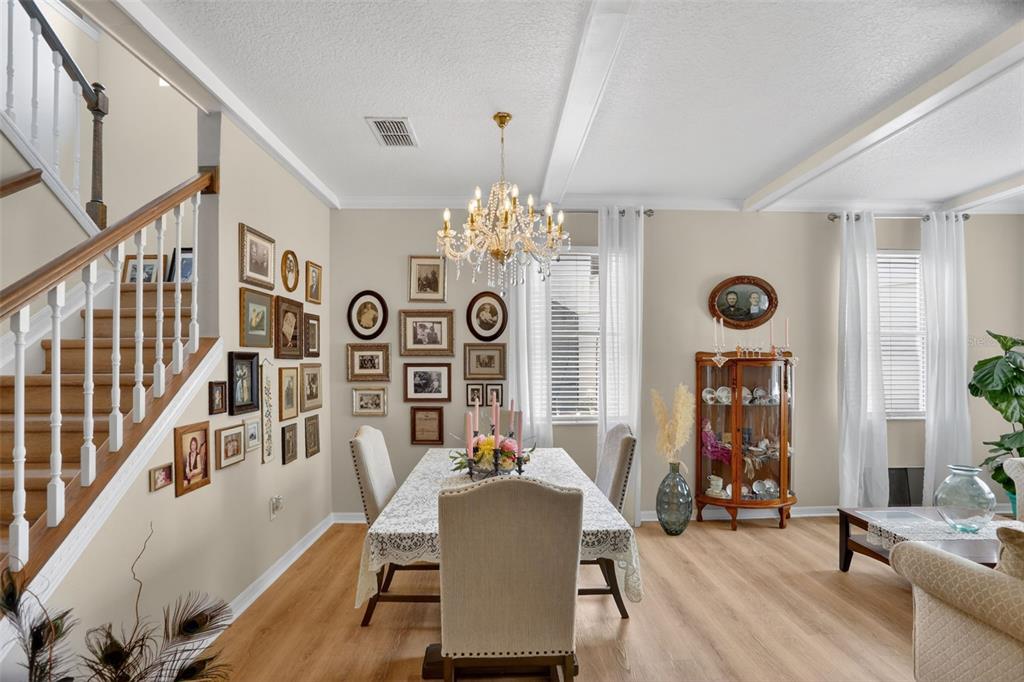 A dining room features a chandelier, a gallery wall, a wooden staircase, and light flooring — 388 SAND RIDGE DRIVE, DAVENPORT, FL