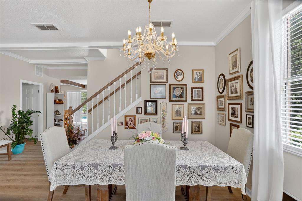 A dining room features a lace-covered table, a crystal chandelier, and a gallery wall — 388 SAND RIDGE DRIVE, DAVENPORT, FL