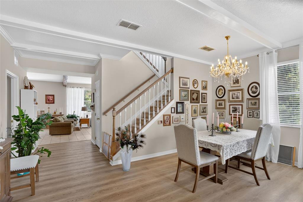 A dining room with a chandelier and gallery wall sits beside a staircase and living area — 388 SAND RIDGE DRIVE, DAVENPORT, FL