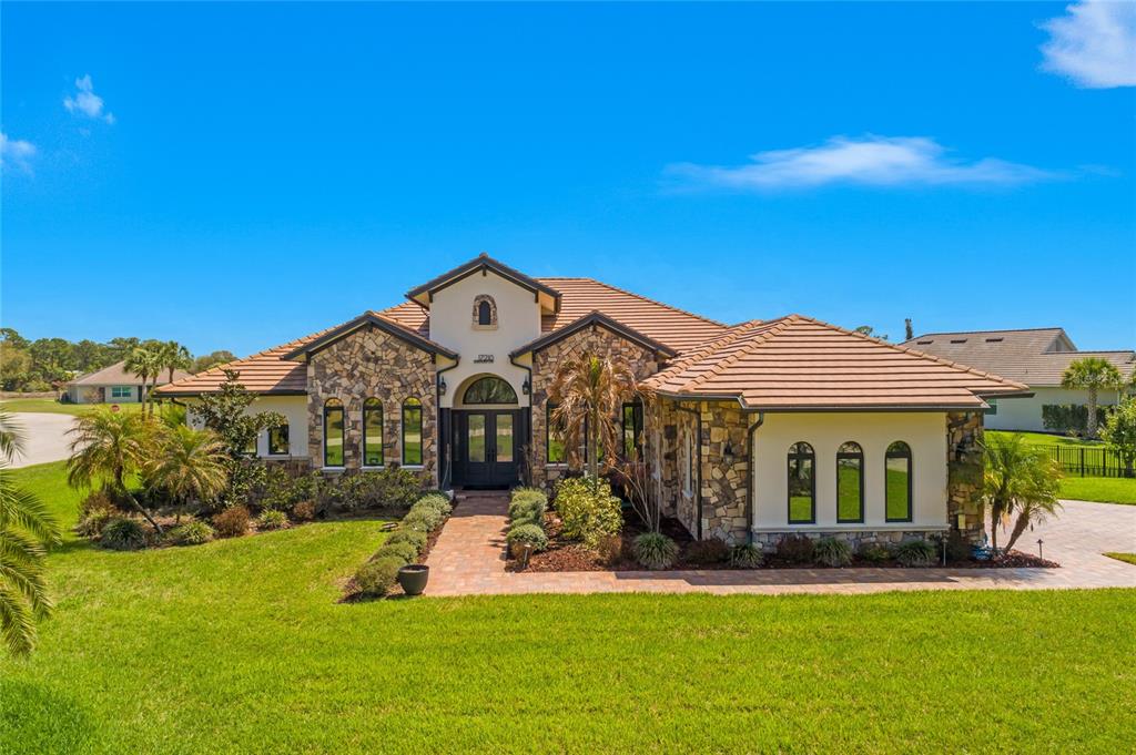 A single-story house with a stone facade, tile roof, and a paved walkway to the entrance — 17210 SERENGETI CIRCLE, ALVA, FL