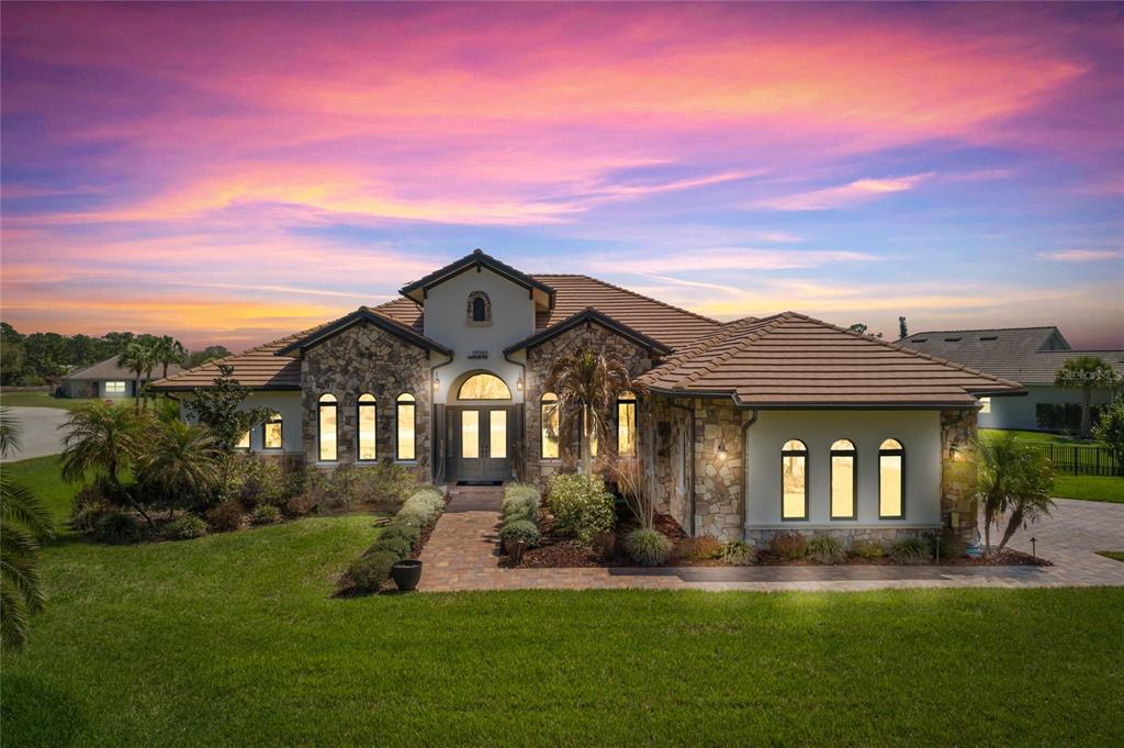 A single-story house with stone siding, a tiled roof, and a paved walkway at sunset — 17210 SERENGETI CIRCLE, ALVA, FL