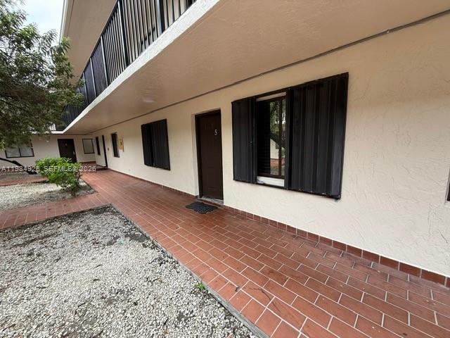 An exterior view of a building with a tiled walkway and dark window shutters — 6278 W 22nd Ct # 5, Hialeah FL 33016, HIALEAH, FL
