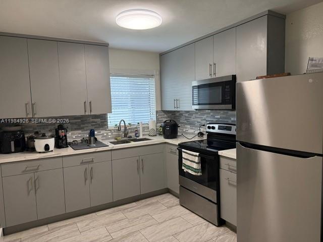 A kitchen features gray cabinets, stainless steel appliances, a tiled backsplash, and light-colored flooring — 6278 W 22nd Ct # 5, Hialeah FL 33016, HIALEAH, FL