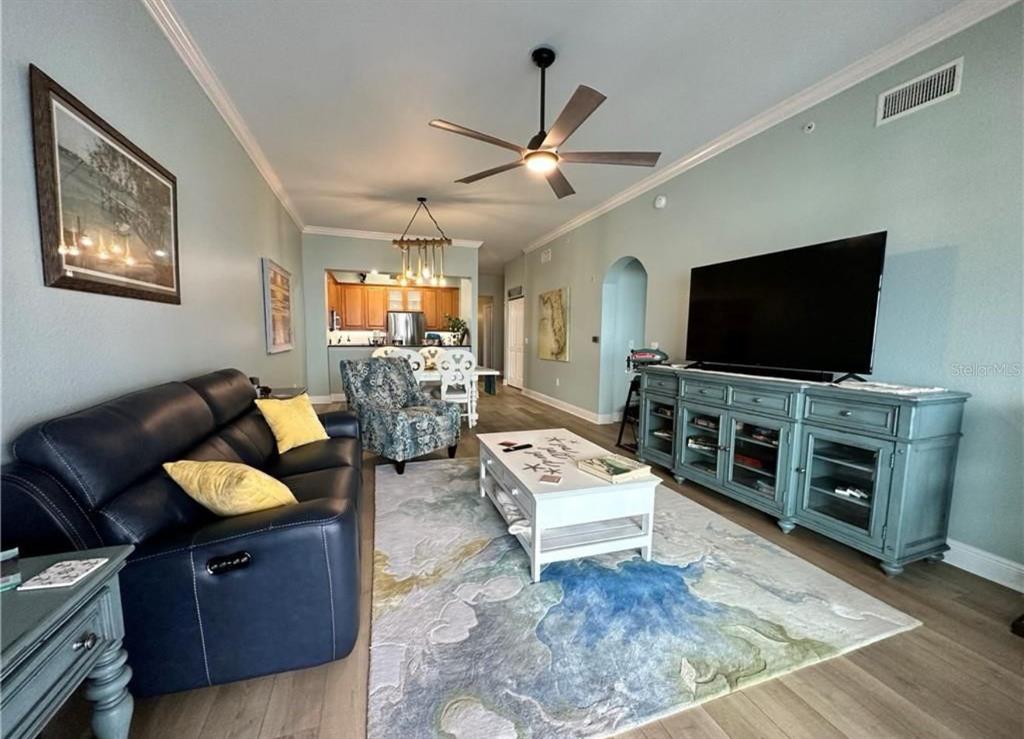 A living room features a dark leather sofa, a blue media console, and a patterned rug — 5114 MELBOURNE STREET UNIT A302, PUNTA GORDA, FL