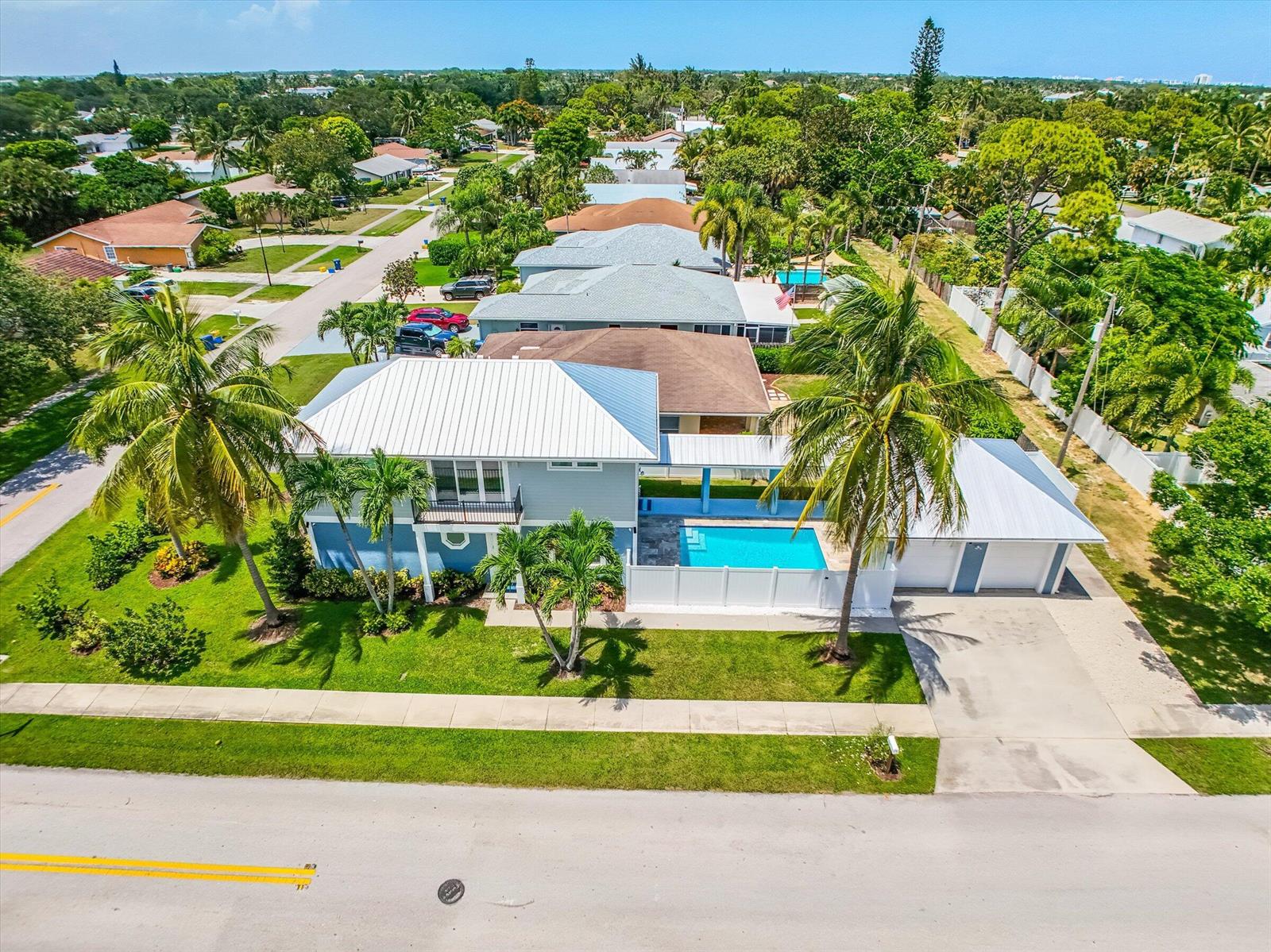 An aerial view of a blue two-story house with a metal roof and private pool — 425 Hugh Street, Jupiter FL 33458, JUPITER, FL