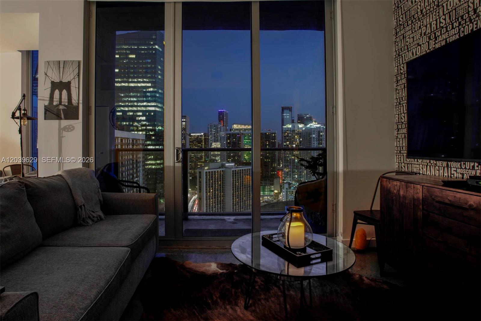 A living room with a gray sofa, glass coffee table, and floor-to-ceiling windows overlooking a city — 151 SE 1st St # 3103, Miami FL 33131, MIAMI, FL