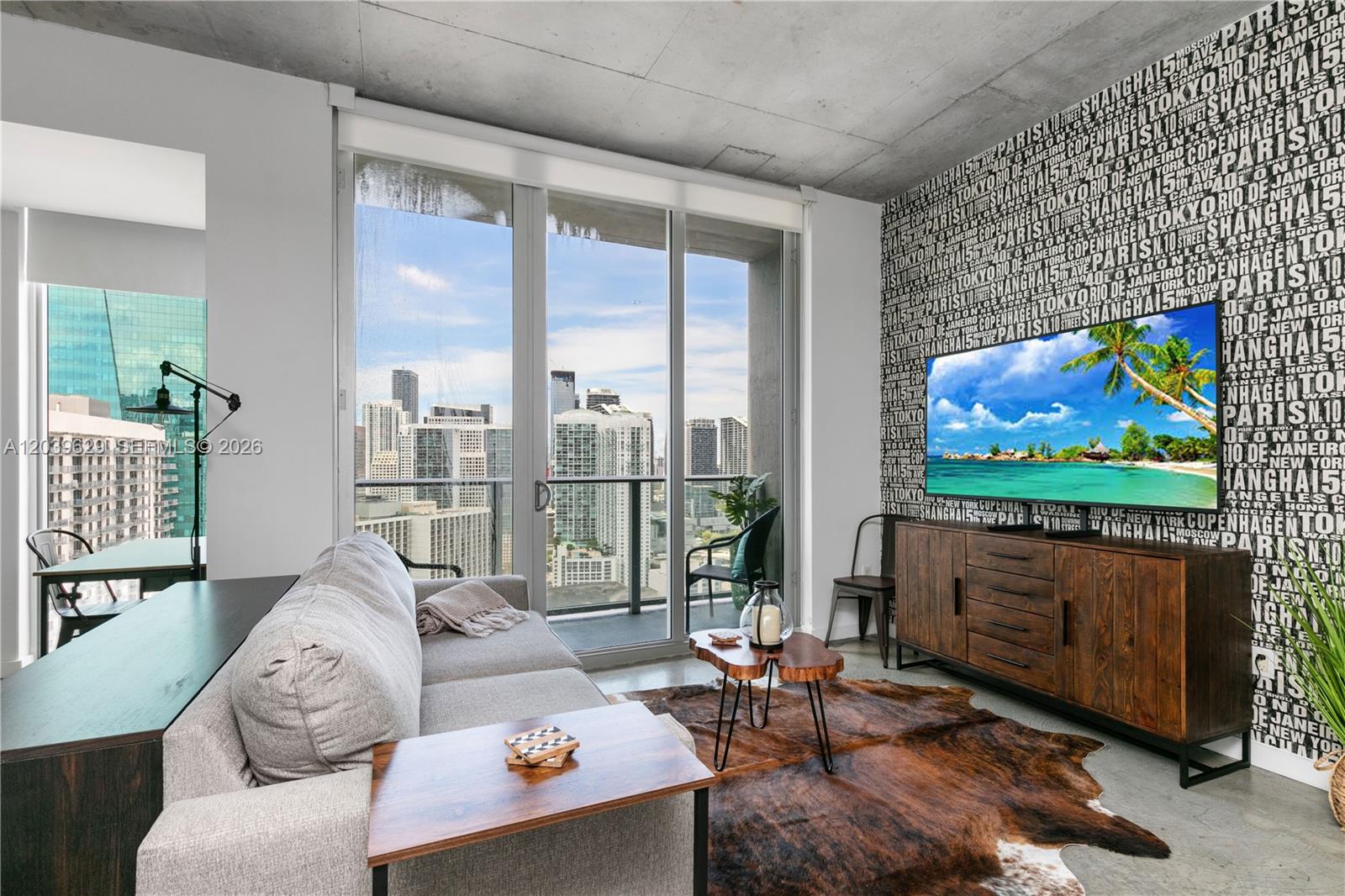 A modern living room features a city view, patterned wallpaper, and a cowhide area rug — 151 SE 1st St # 3103, Miami FL 33131, MIAMI, FL
