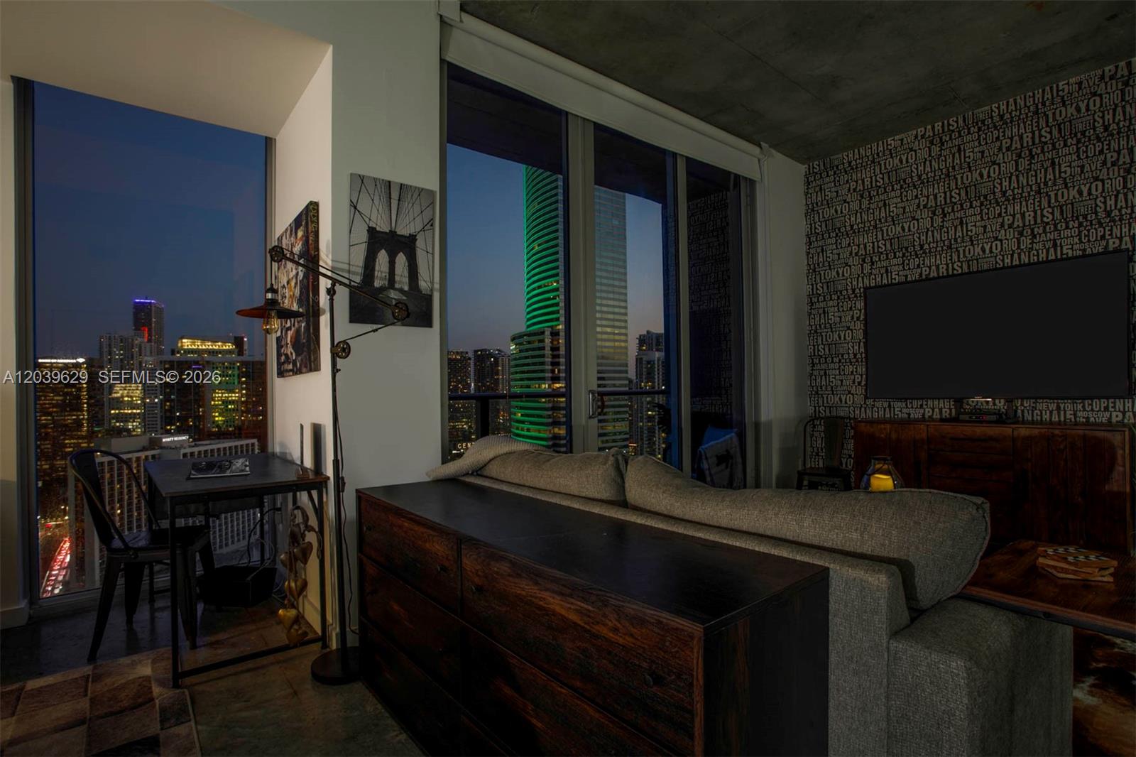 A modern living room features a dark wood dresser, a sofa, and floor-to-ceiling city views — 151 SE 1st St # 3103, Miami FL 33131, MIAMI, FL