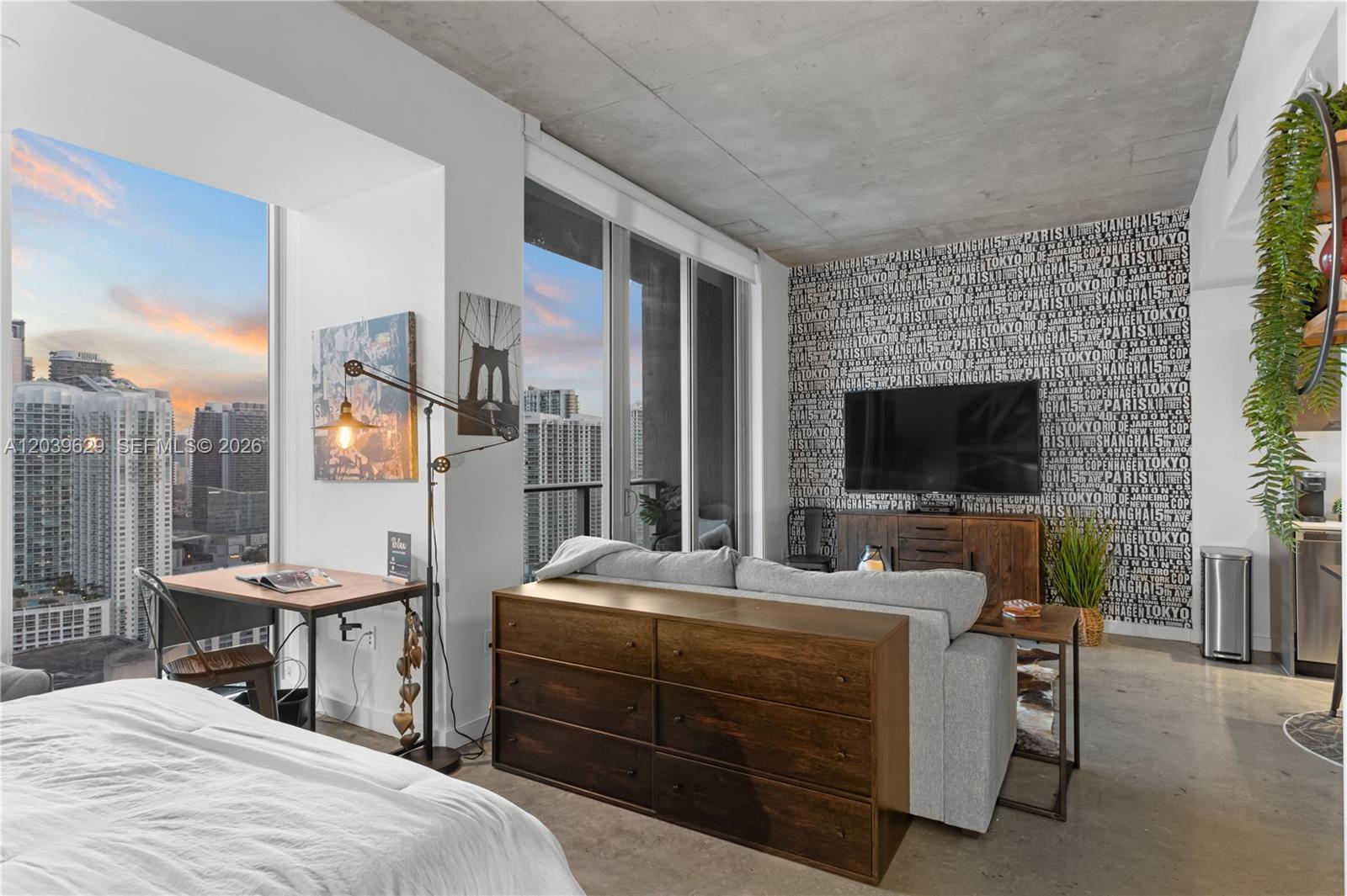 A modern studio apartment features a concrete ceiling, city views, and a graphic wallpaper accent wall — 151 SE 1st St # 3103, Miami FL 33131, MIAMI, FL