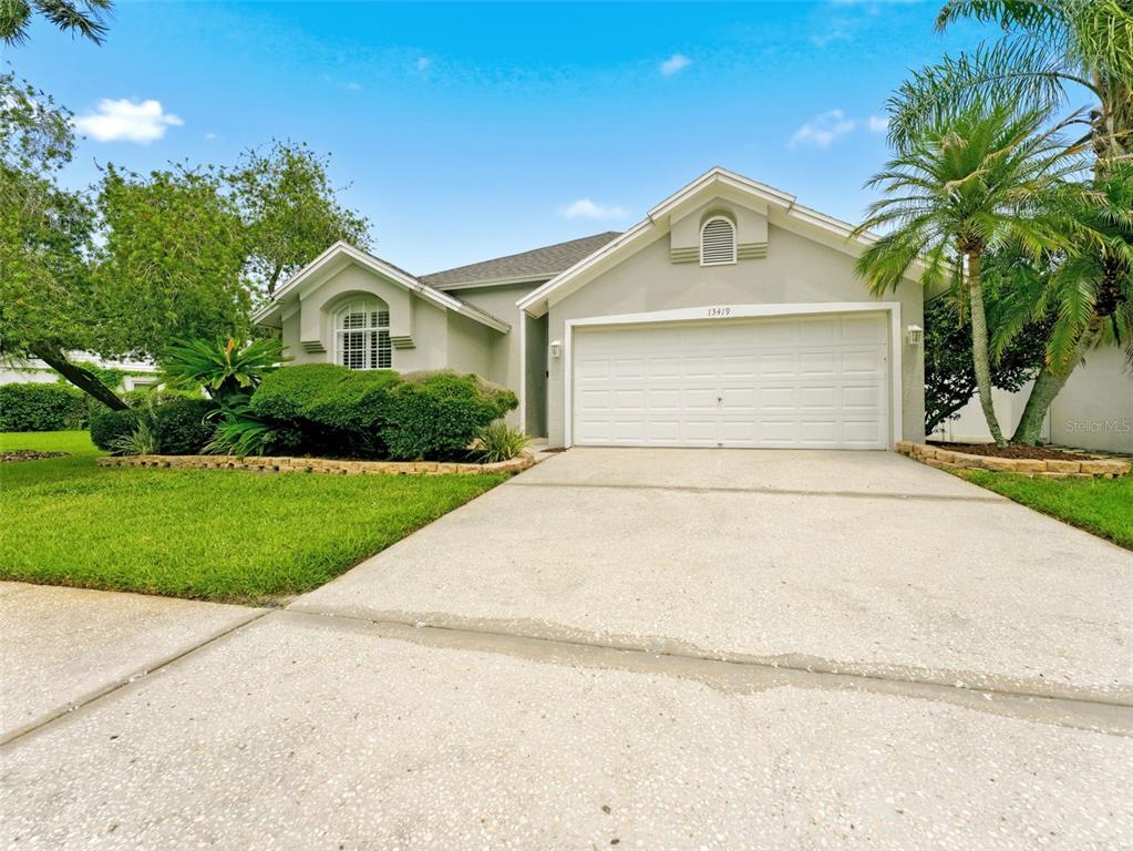 A single-story house with a white garage, arched window, and landscaped front yard — 13419 EUDORA PLACE, TAMPA, FL