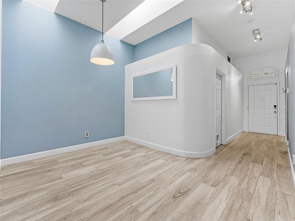 A room with light blue walls, wood-look flooring, a curved white wall, and a pendant light — 13419 EUDORA PLACE, TAMPA, FL