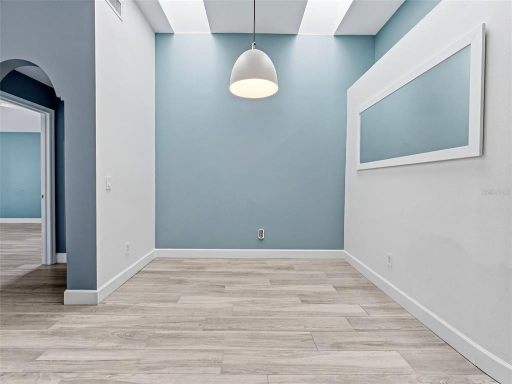 A dining area features light wood-look flooring, a blue accent wall, and a pendant light — 13419 EUDORA PLACE, TAMPA, FL