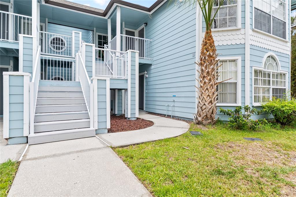 A light blue multi-story apartment building features a wooden staircase leading to an upper balcony — 2036 ROYAL BAY BOULEVARD UNIT 59, KISSIMMEE, FL