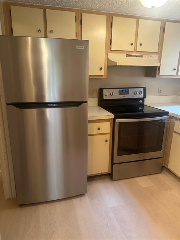 A kitchen features stainless steel appliances, light-colored cabinets, and wood-look flooring — 1940 LAKE ATRIUMS CIRCLE UNIT 93, ORLANDO, FL