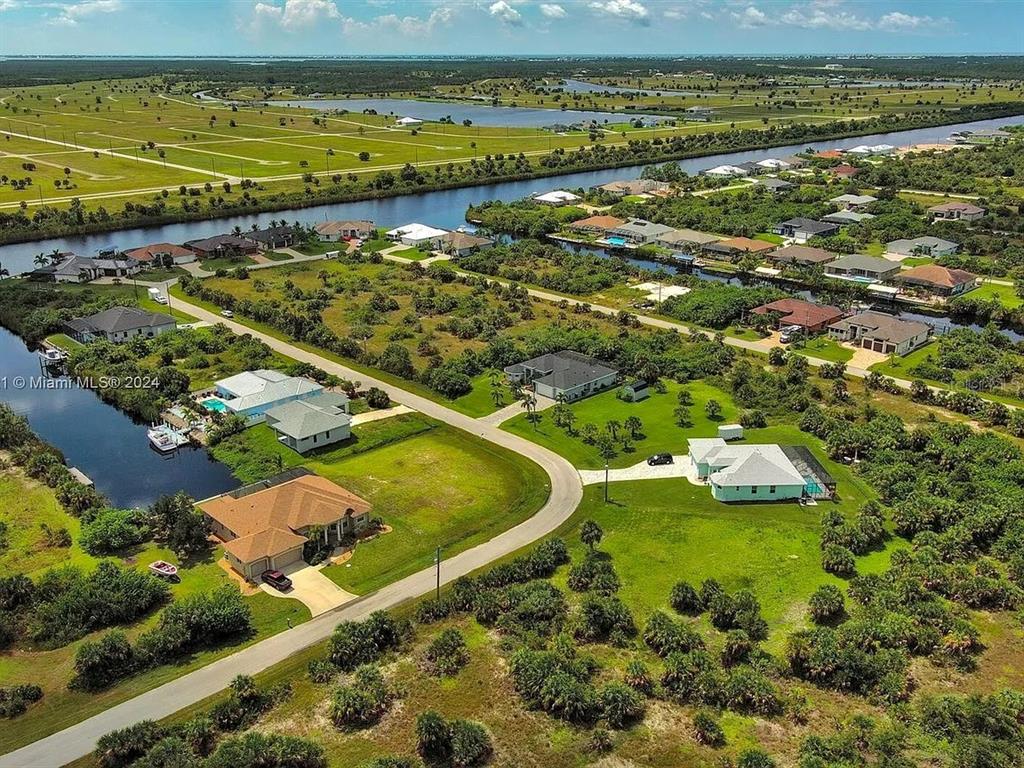 An aerial view shows several houses with pools situated along a canal in a rural area — 10705 RAINSVILLE STREET, PORT CHARLOTTE, FL