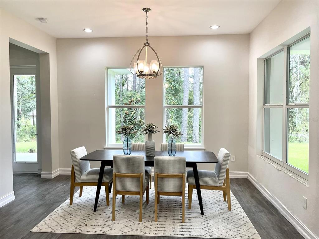A dining room with a dark table, six striped chairs, and a chandelier on a rug — 4836 MAJESTIC HILLS LOOP, BROOKSVILLE, FL