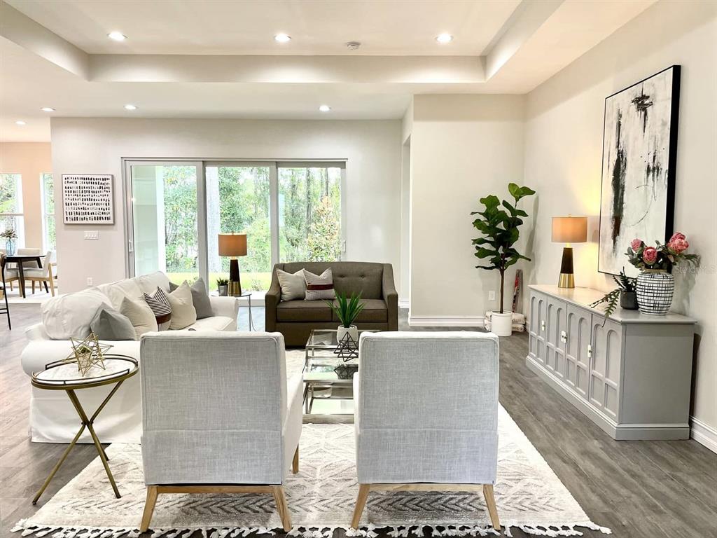 A living room features a white sofa, two armchairs, a brown loveseat, and a console table — 4836 MAJESTIC HILLS LOOP, BROOKSVILLE, FL