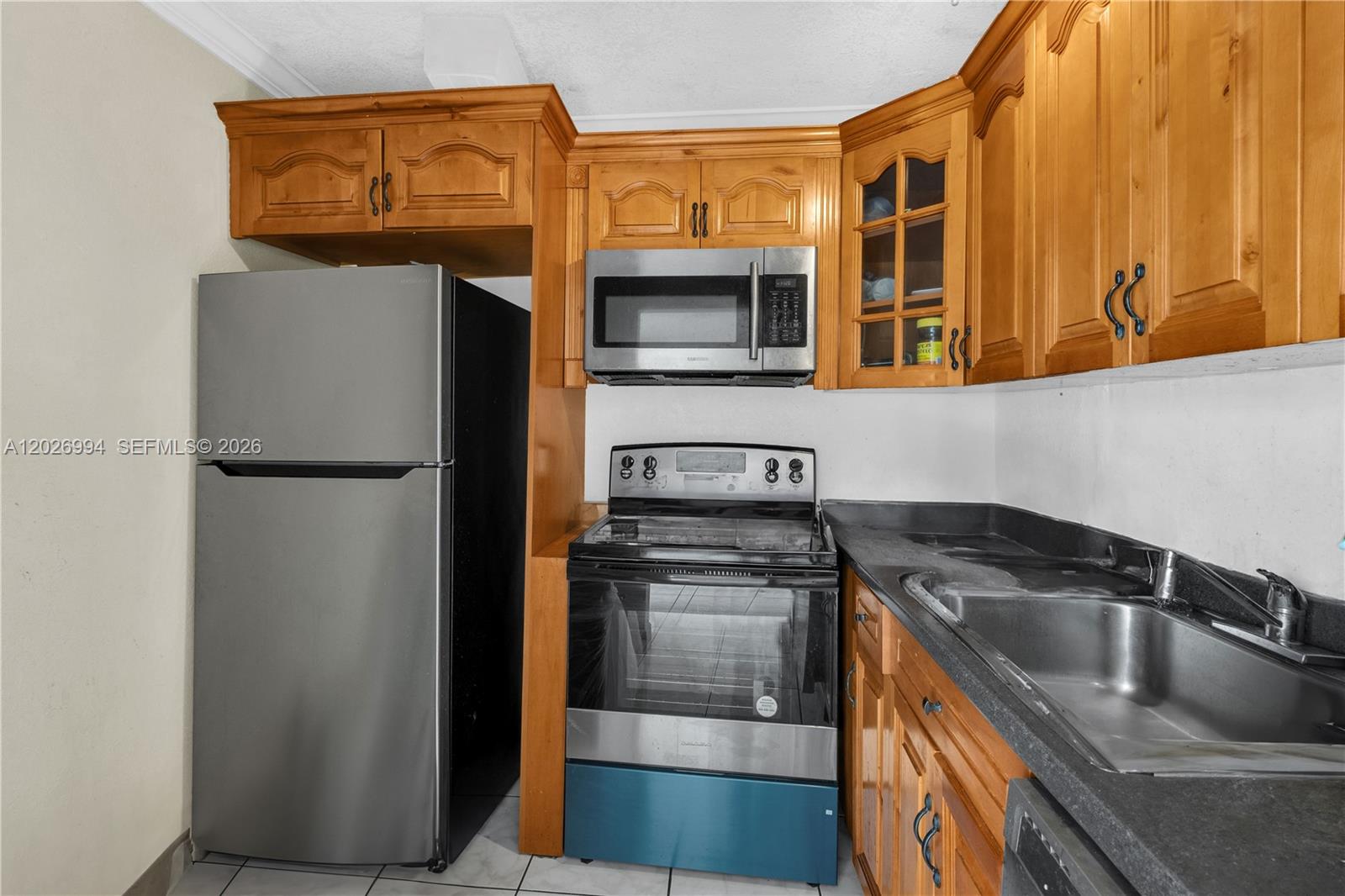 A kitchen features wood cabinets, stainless steel appliances, and a dark countertop with a sink — 496 NW 165th St Rd # 616, Miami FL 33169, MIAMI, FL