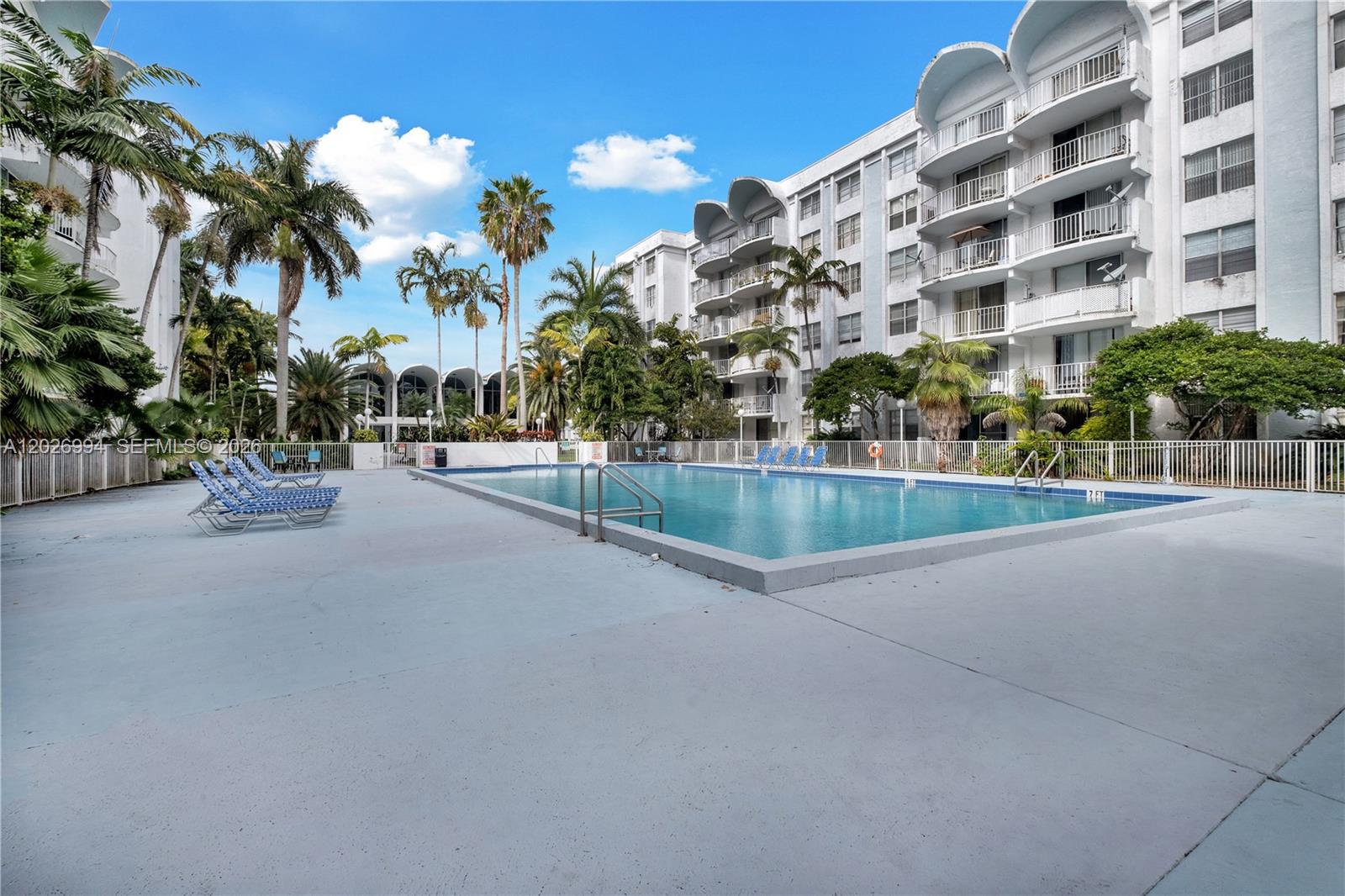 An outdoor swimming pool is surrounded by a concrete deck, lounge chairs, and palm trees — 496 NW 165th St Rd # 616, Miami FL 33169, MIAMI, FL