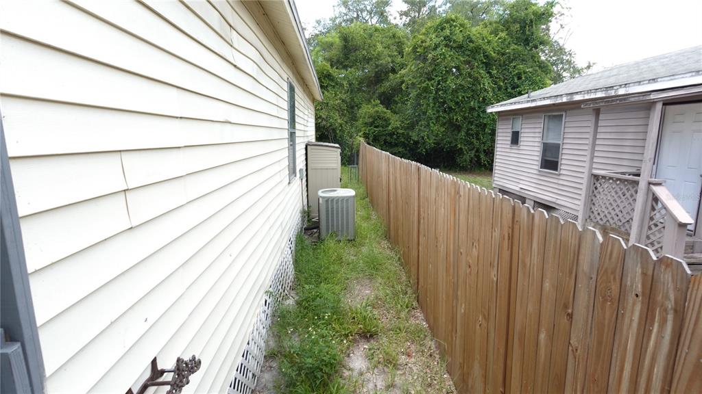 A narrow side yard between two houses features a wooden fence and an air conditioner — 3110 GORDON COURT, TAMPA, FL