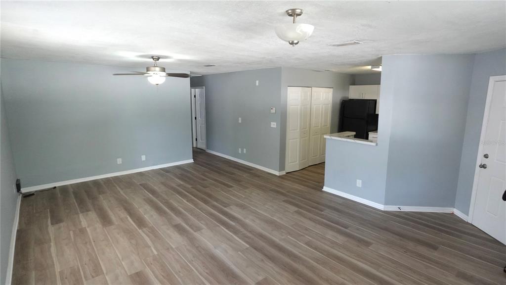 An open-concept living area features light gray walls, wood-look flooring, and a kitchen pass-through — 3110 GORDON COURT, TAMPA, FL