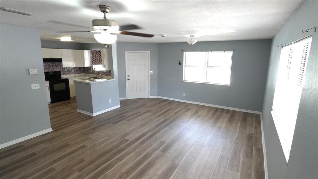 An open-concept living area features light gray walls, wood-look flooring, and an adjacent kitchen — 3110 GORDON COURT, TAMPA, FL