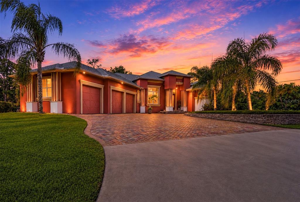 A red house with a paved driveway and palm trees under a sunset sky — 3257 WENONA DRIVE, NORTH PORT, FL