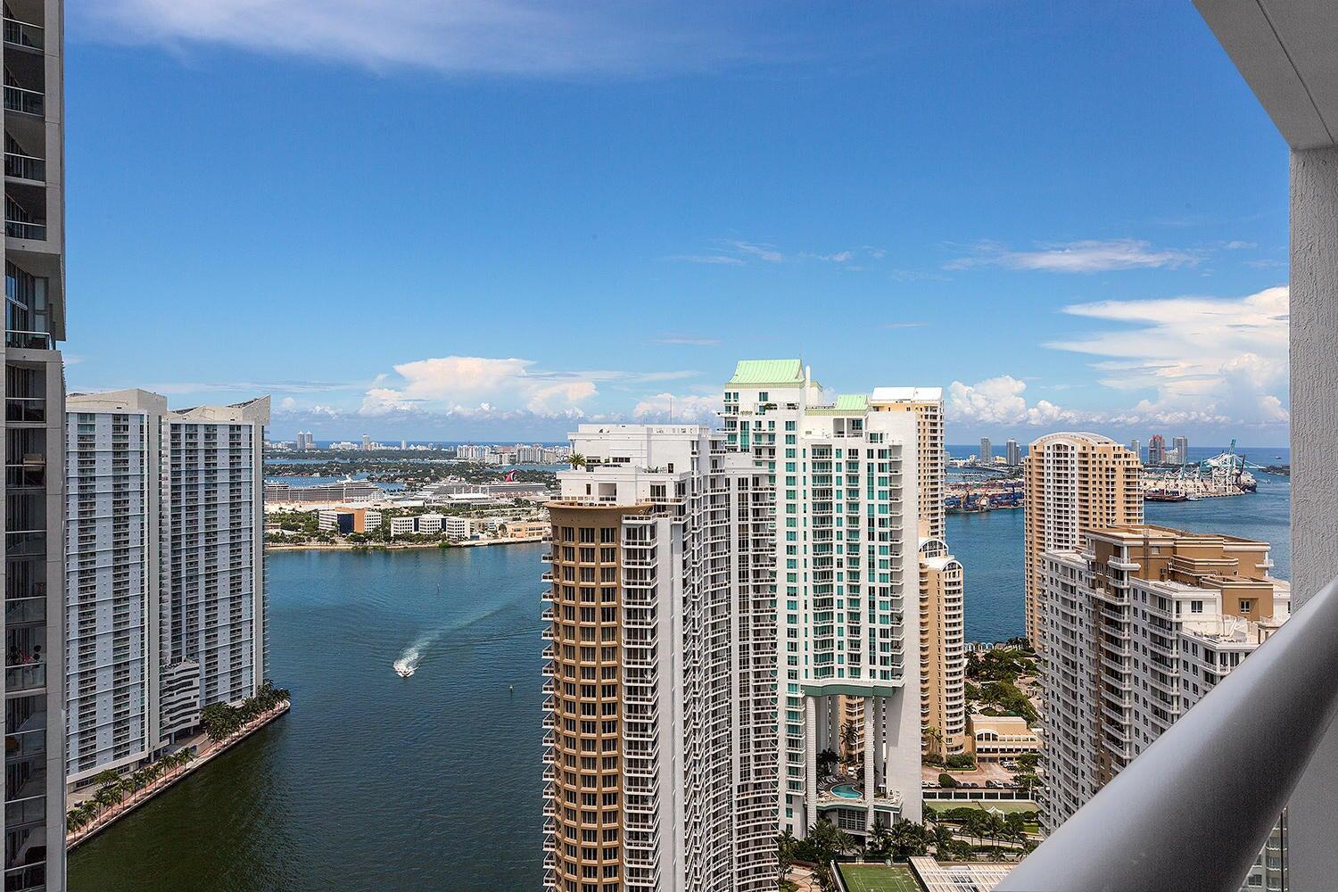 A high-angle view from a balcony overlooking a bay, skyscrapers, and a cruise ship terminal — 495 Brickell Avenue # 4010, Miami FL 33131, MIAMI, FL