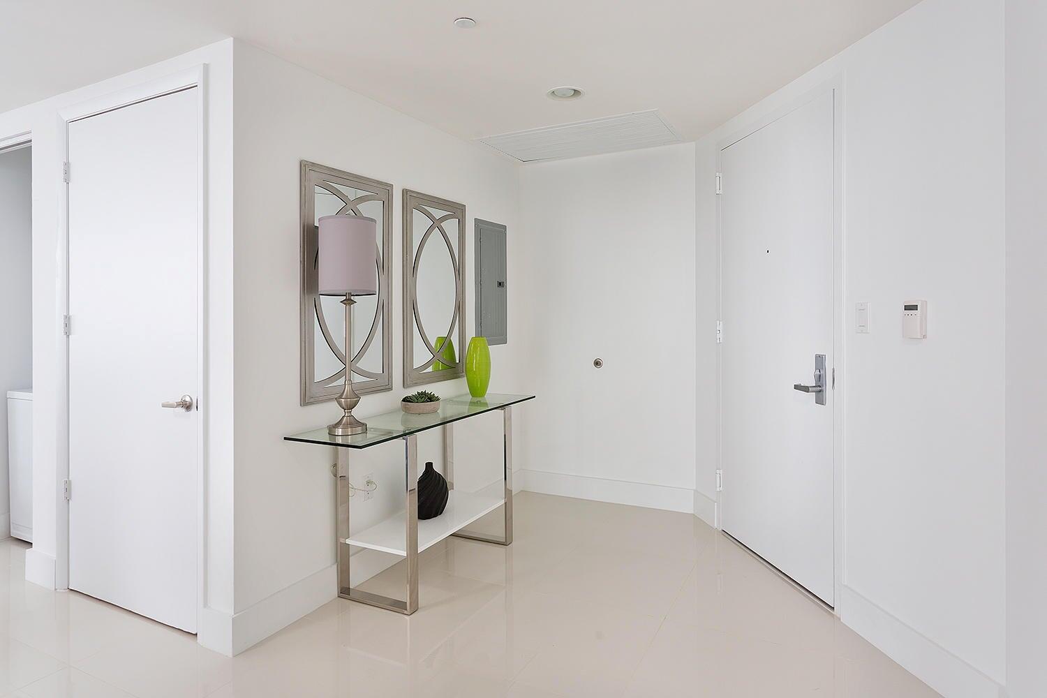 A bright entryway features a glass console table, two wall mirrors, and white tiled floors — 495 Brickell Avenue # 4010, Miami FL 33131, MIAMI, FL