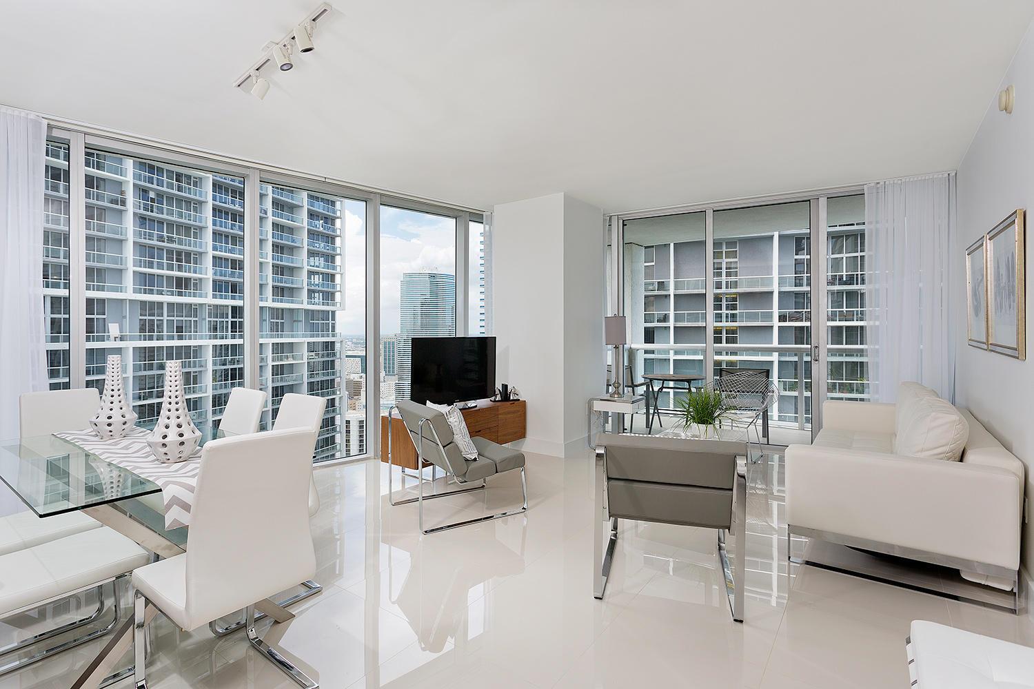 A modern living and dining room with white tile floors, glass walls, and city views — 495 Brickell Avenue # 4010, Miami FL 33131, MIAMI, FL