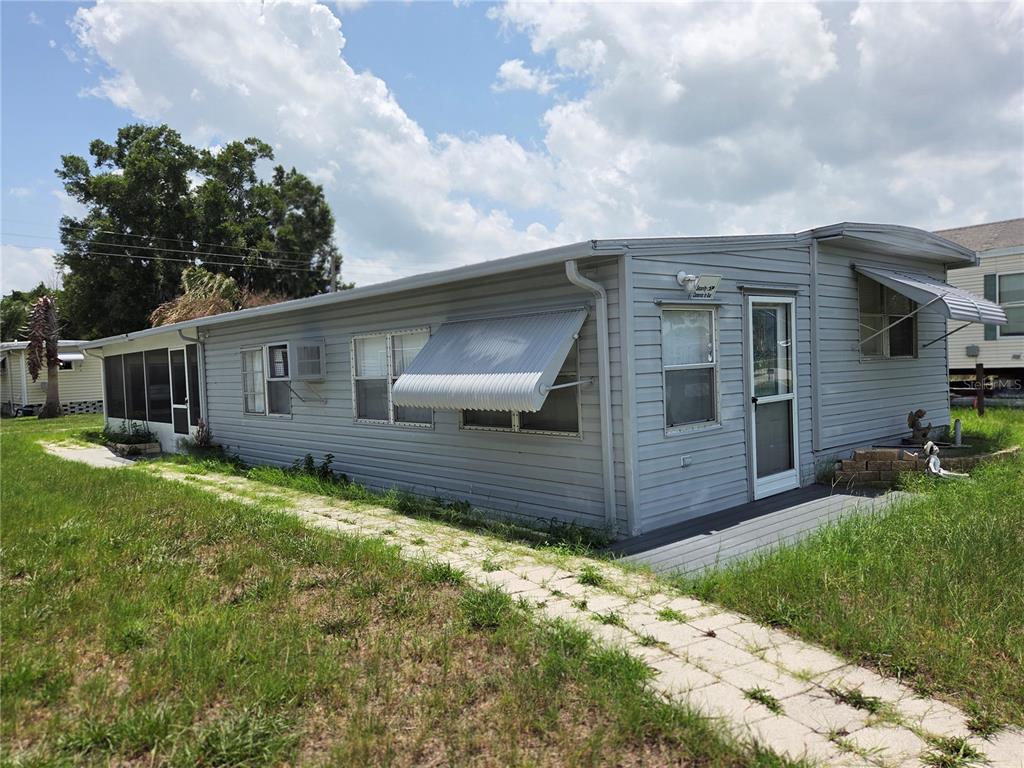A light gray mobile home with metal awnings and a screened porch sits on grass — 6240 CONNECTICUT STREET, ZEPHYRHILLS, FL
