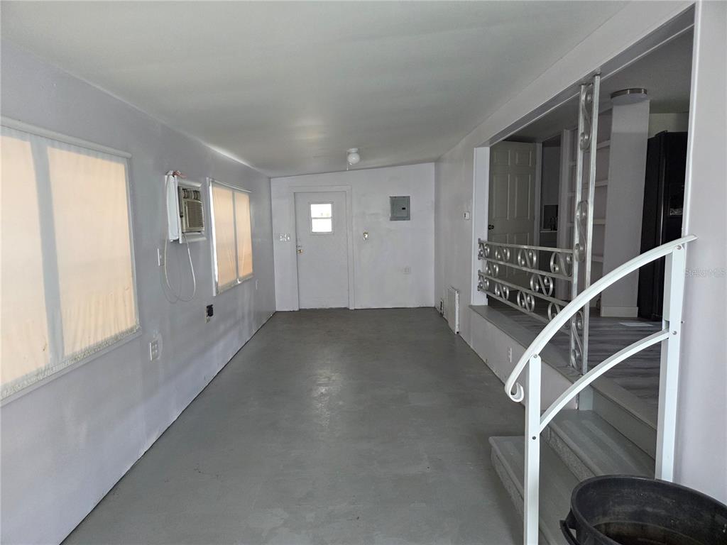 A long, enclosed porch with gray flooring, white walls, a window air conditioner, and stairs — 6240 CONNECTICUT STREET, ZEPHYRHILLS, FL