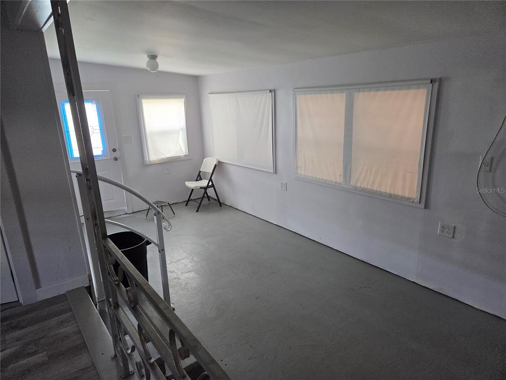 A sunroom with gray painted floors, white walls, and a metal staircase railing — 6240 CONNECTICUT STREET, ZEPHYRHILLS, FL