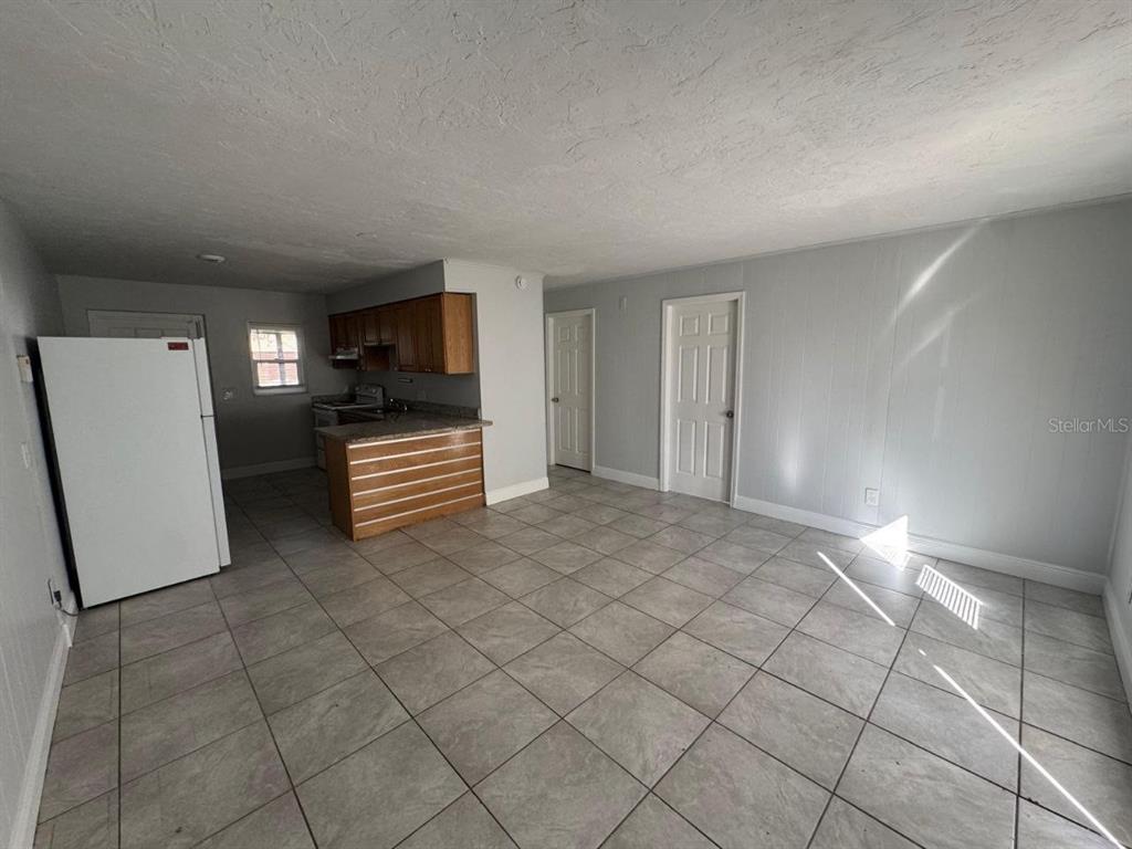 An open-concept kitchen and living area with tile flooring, white walls, and wood cabinets — 1392 KING STREET UNIT 1392, BARTOW, FL