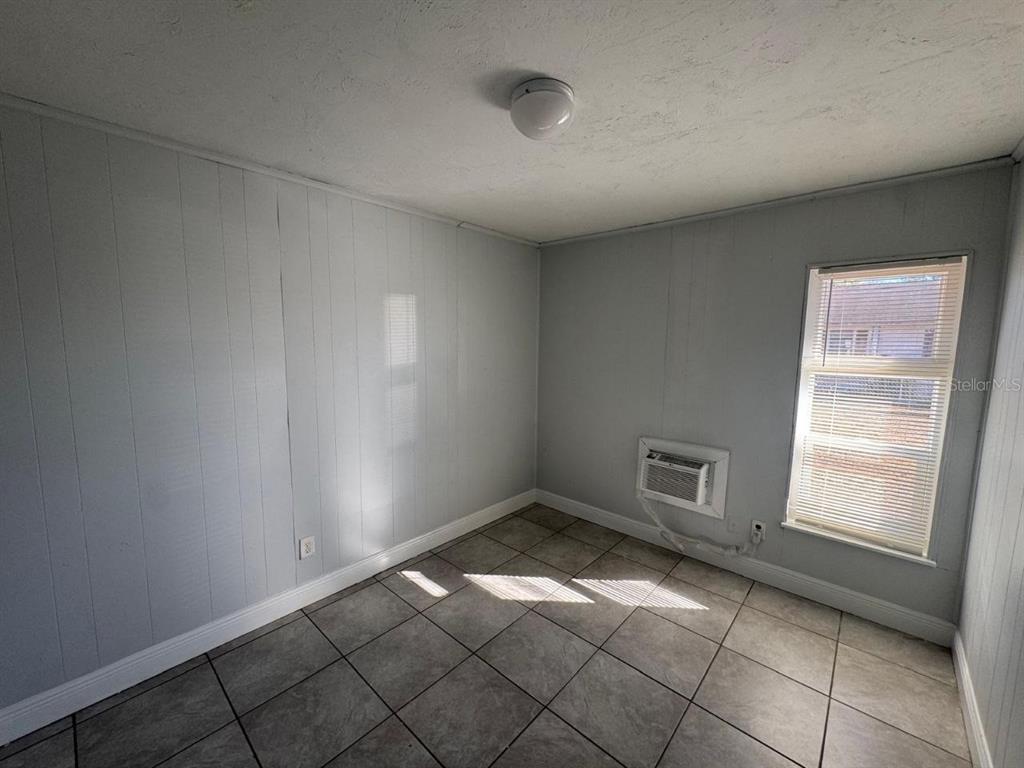 A small room with light gray paneled walls, tile flooring, a window, and a wall-mounted AC — 1392 KING STREET UNIT 1392, BARTOW, FL