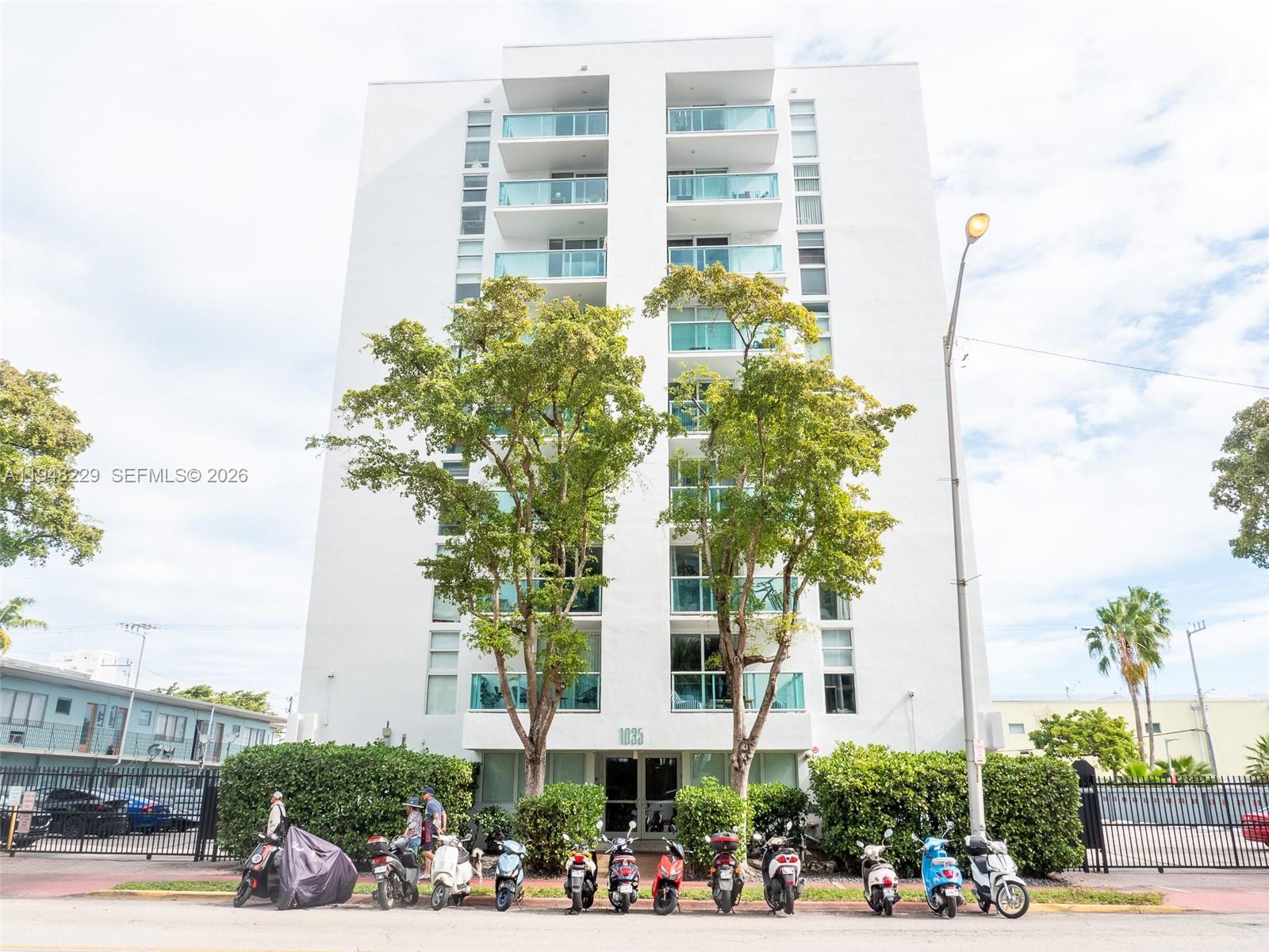 A multi-story white apartment building features balconies and a row of parked scooters outside — 1035 West Ave, Miami Beach FL 33139, MIAMI BEACH, FL