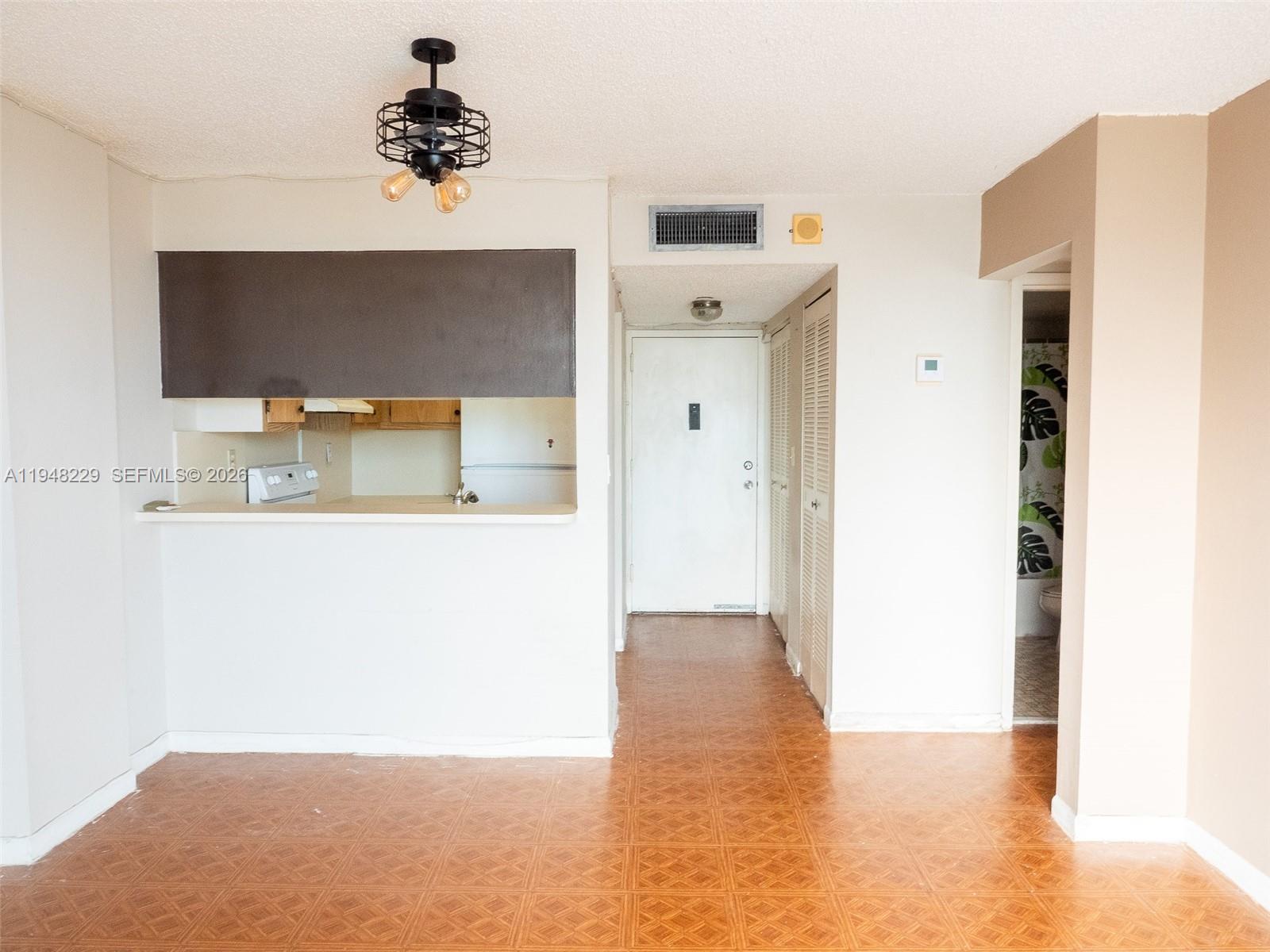 This interior view shows a kitchen pass-through, a hallway with a white door, and tiled flooring — 1035 West Ave, Miami Beach FL 33139, MIAMI BEACH, FL