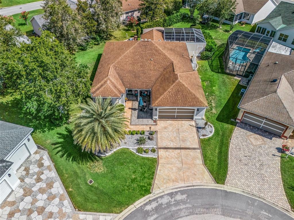An aerial view shows a single-story house with a brown roof, driveway, and palm tree — 609 ORTEGA WAY, THE VILLAGES, FL