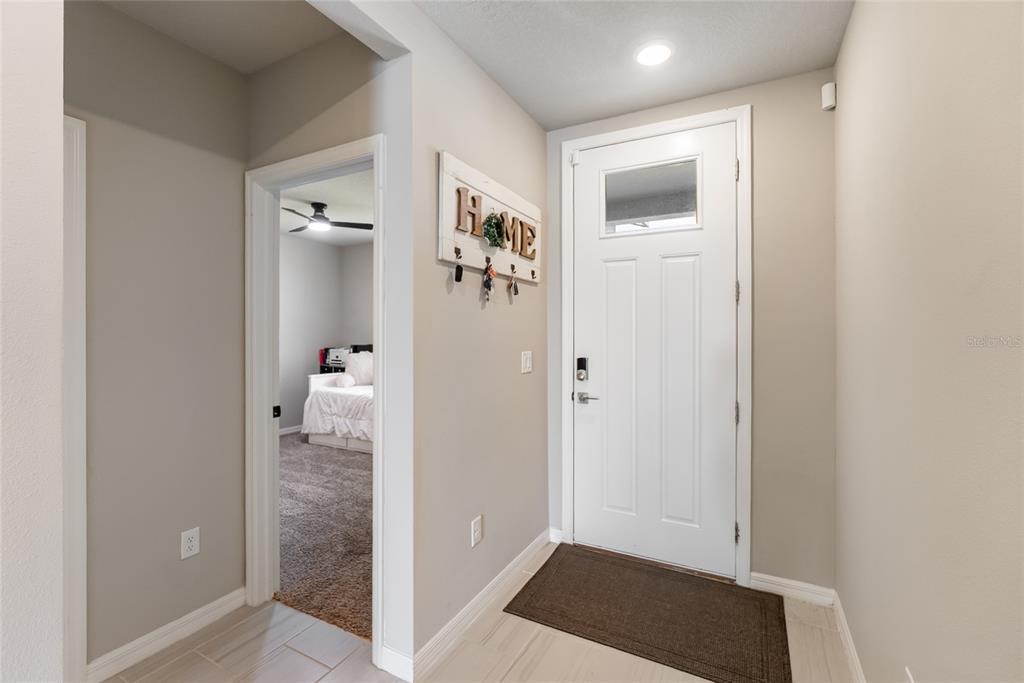 An entryway features a white front door, tile flooring, and a doorway leading to a bedroom — 7124 AMELIA RIVER DRIVE, PARRISH, FL