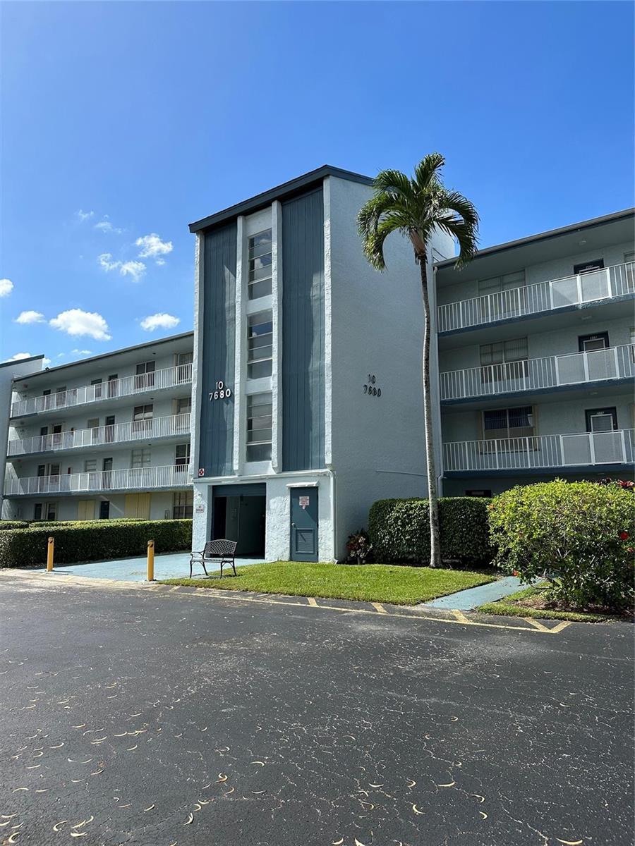 A view of a building exterior with a walkway, windows, and a glass door — 7680 NW 18th Street # 406, Margate FL 33063, MARGATE, FL
