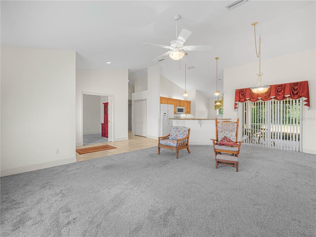 A living room with gray carpet, two chairs, and an open kitchen in the background — 528 GREENWAY DRIVE, LAKE WALES, FL