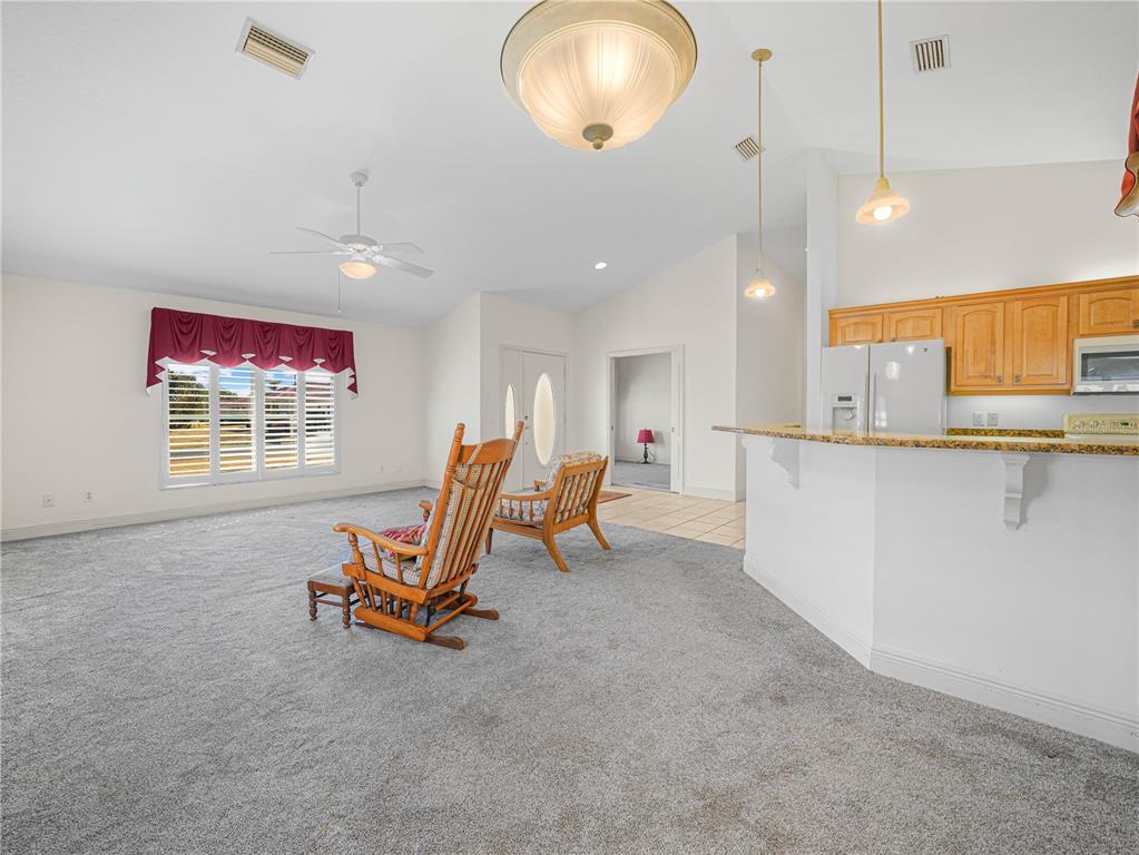 A living room with gray carpet, a kitchen island, and two wooden rocking chairs — 528 GREENWAY DRIVE, LAKE WALES, FL