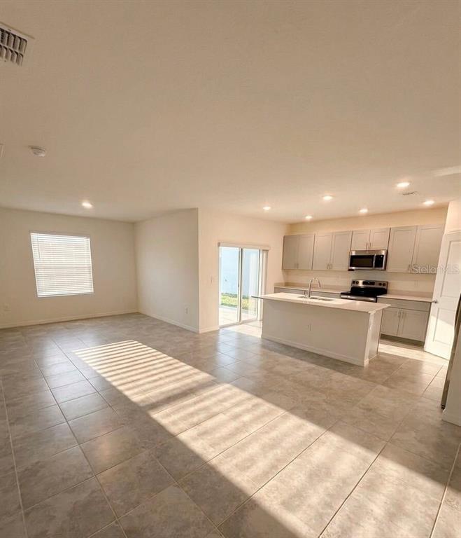 An open-concept kitchen with a center island and light-colored cabinets overlooks a tiled living area — 5443 ISLA SAONA DRIVE, KISSIMMEE, FL