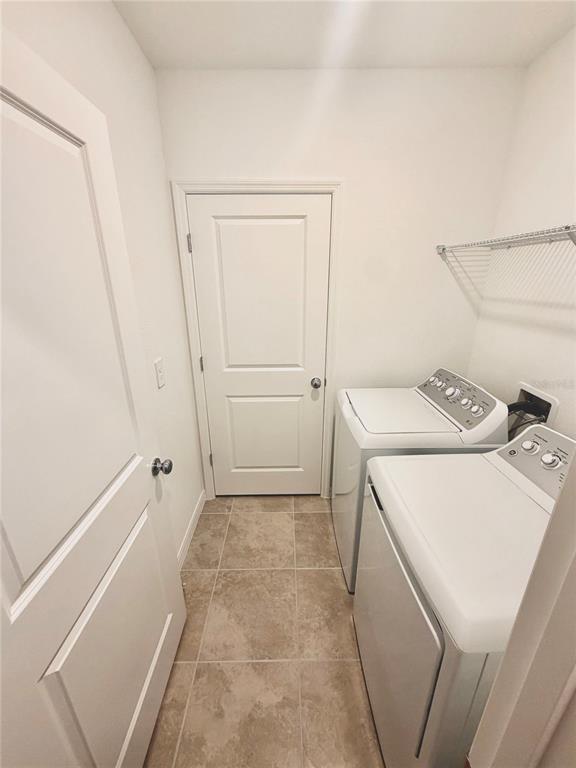 A laundry room features white appliances, tile flooring, and a white door — 5443 ISLA SAONA DRIVE, KISSIMMEE, FL
