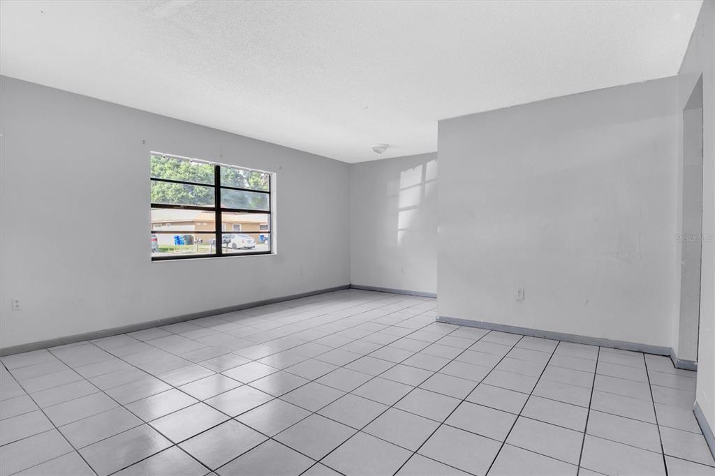 A bright, empty room features white walls, a single window, and light-colored tiled flooring — 2464 CHESTNUT WOODS DRIVE, LAKELAND, FL
