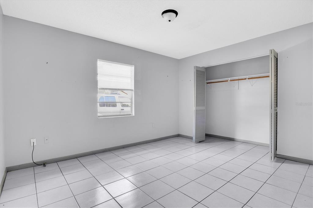 An empty bedroom features white walls, a tiled floor, a window, and a closet — 2464 CHESTNUT WOODS DRIVE, LAKELAND, FL